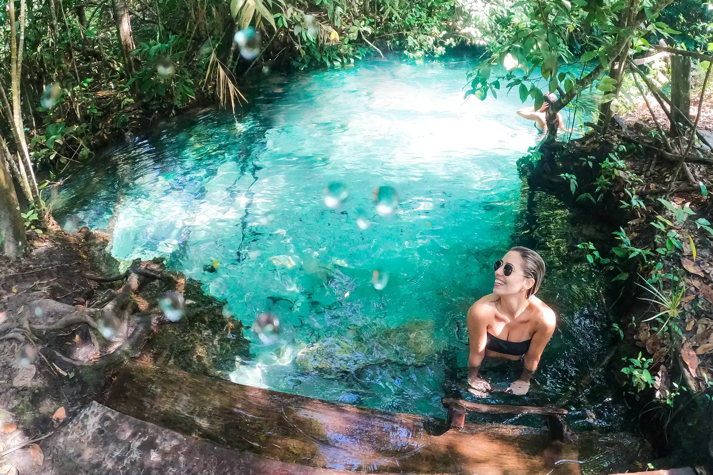 Una viajera dentro de un fervedouro de aguas turquesa, rodeada por la selva del Jalapão